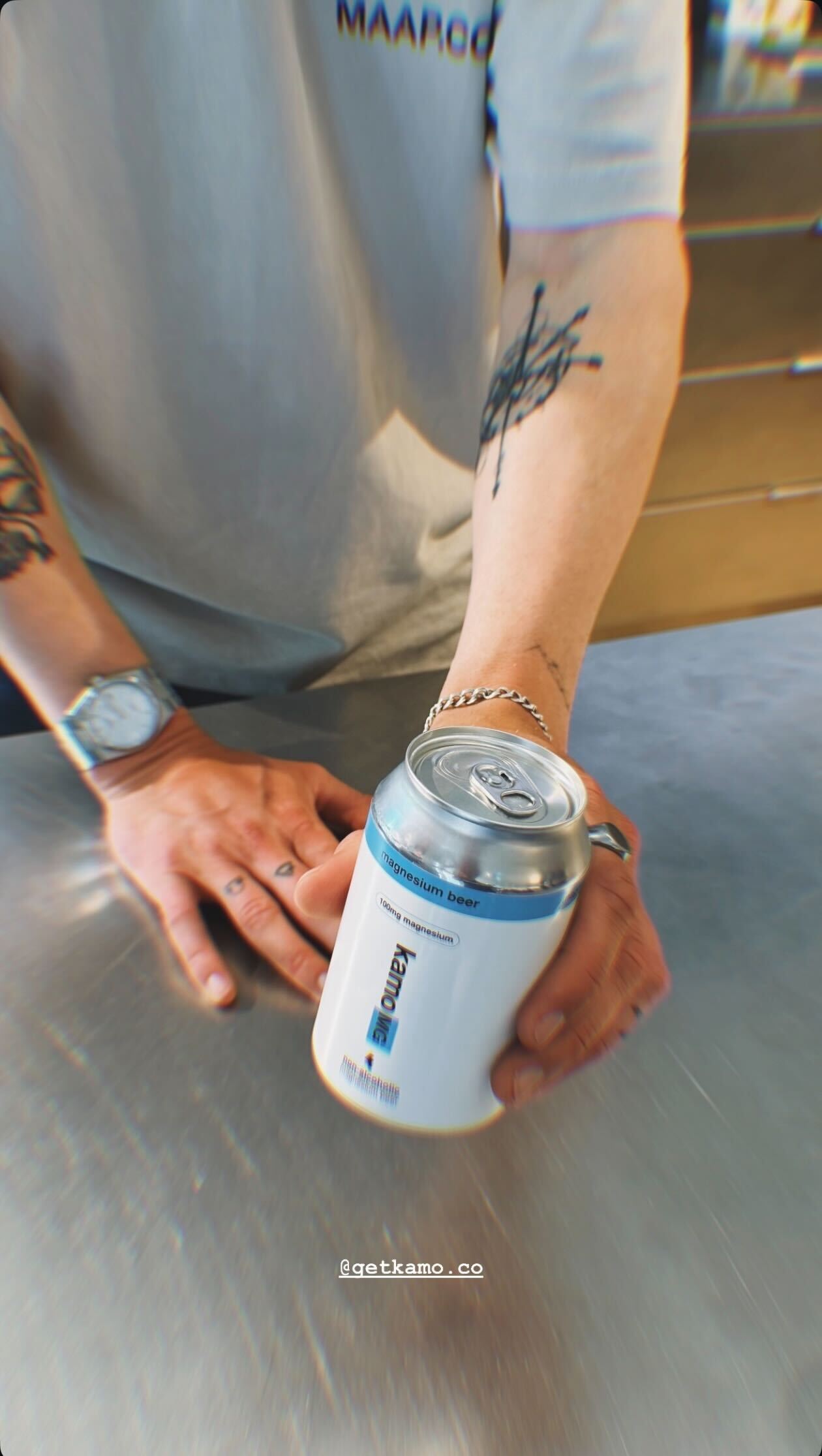Person holding a can with a visible brand logo on a metallic surface